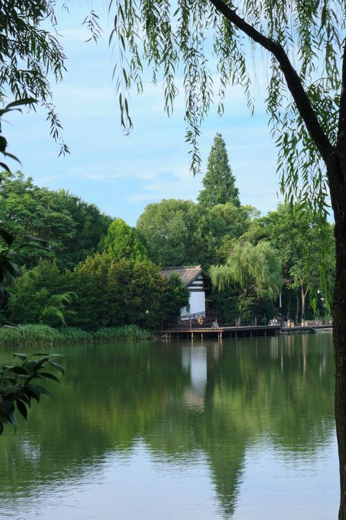 Free Idyllic scene of a house by a green lake with lush trees and a jetty. Stock Photo