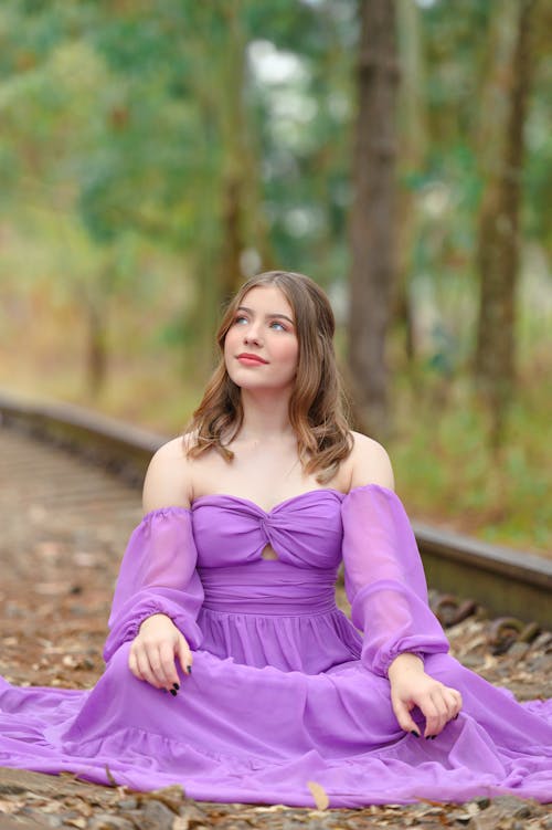 Woman in Evening Dress Sitting on Rail Tracks