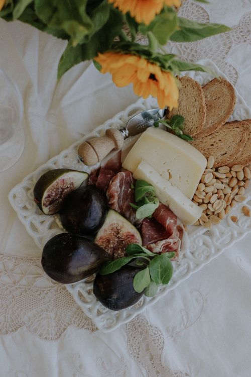 Free Elegant cheese platter with figs, nuts, and sunflowers on a lace tablecloth. Stock Photo