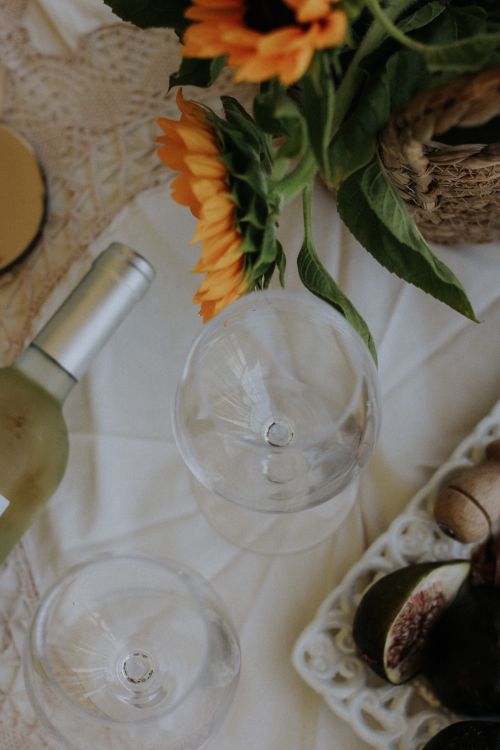 Free A charming top view of a table with sunflowers, wine, and fruit for a perfect gathering. Stock Photo