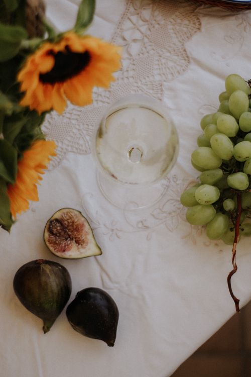 Free Beautiful arrangement of grapes, figs, and sunflowers on a lace tablecloth. Stock Photo