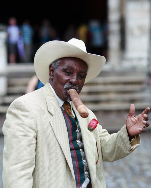 Free Elderly man in suit and hat enjoying a cigar with a confident pose outdoors. Stock Photo