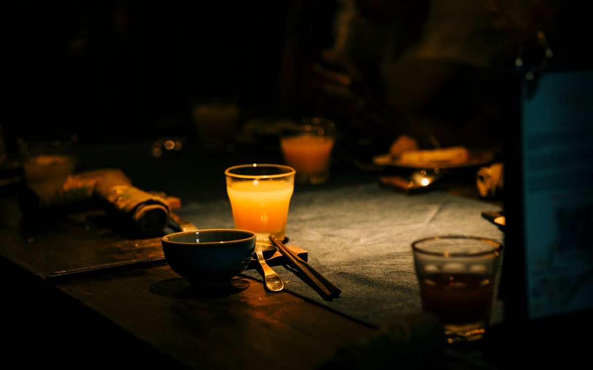 A dimly lit dinner table with a glass of juice and table setting, creating a warm atmosphere.