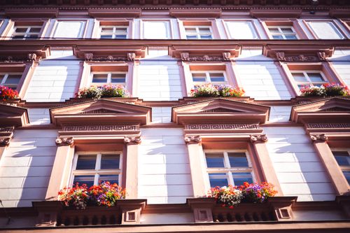 Free Low angle shot of a neoclassical building facade adorned with vibrant flowerpots. Stock Photo
