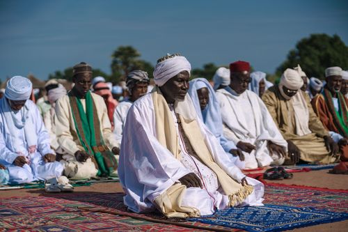 Free Group of men in traditional clothing engaged in Muslim prayer outdoors. Stock Photo