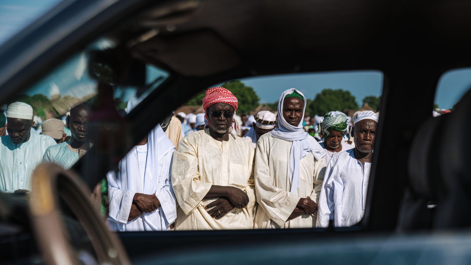Crowd in traditional clothing standing behind car window, Chad