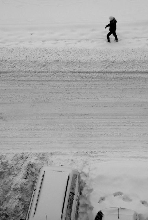Free A person walks on a snowy street, captured from a high angle, showcasing winter scenery. Stock Photo