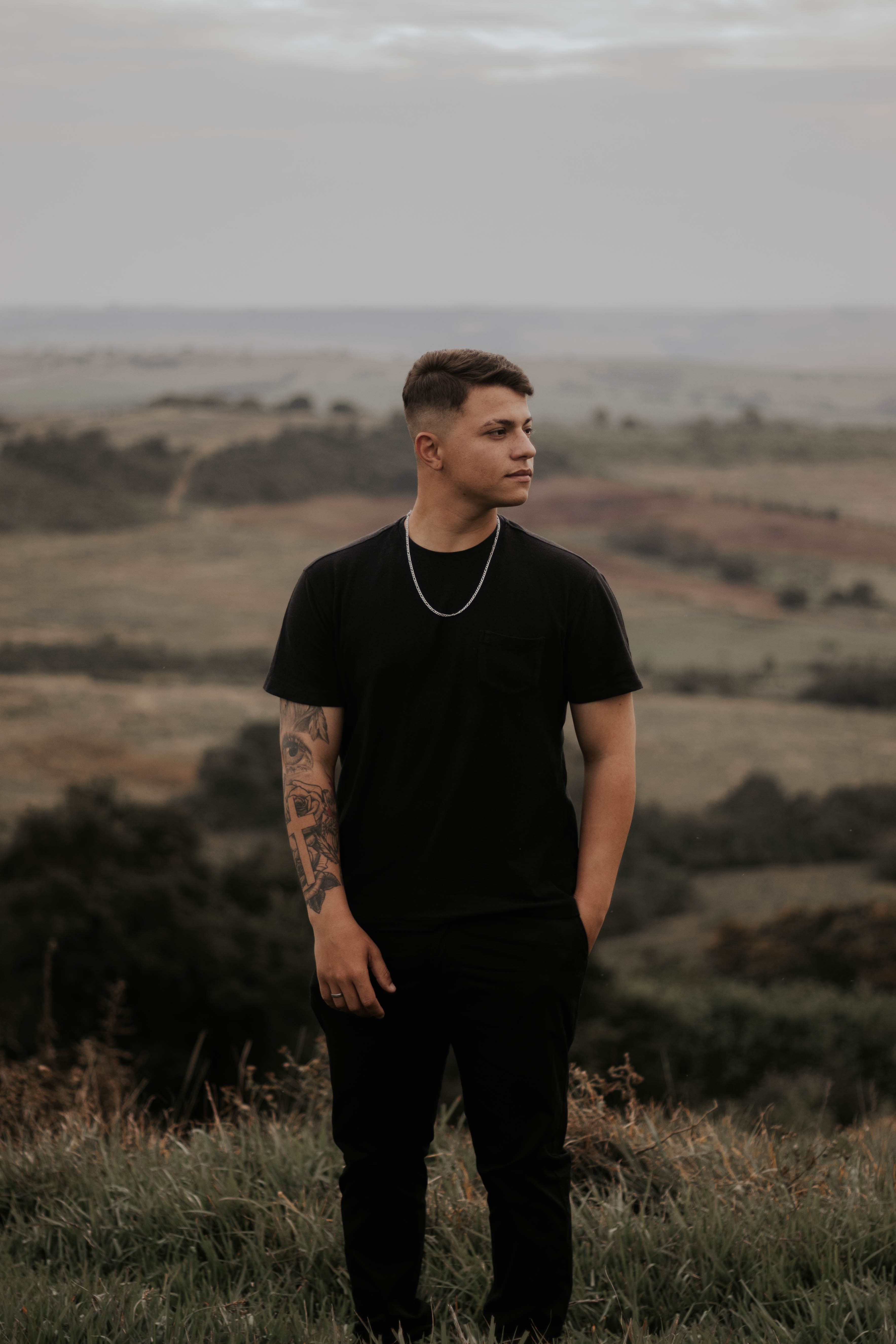 Young man standing in an expansive landscape at Quinta do Sol, Brazil, during a warm day.