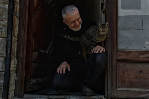 Man Sitting with Cat in House Doorway
