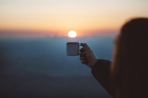 显示白色杯子的人在焦点摄影