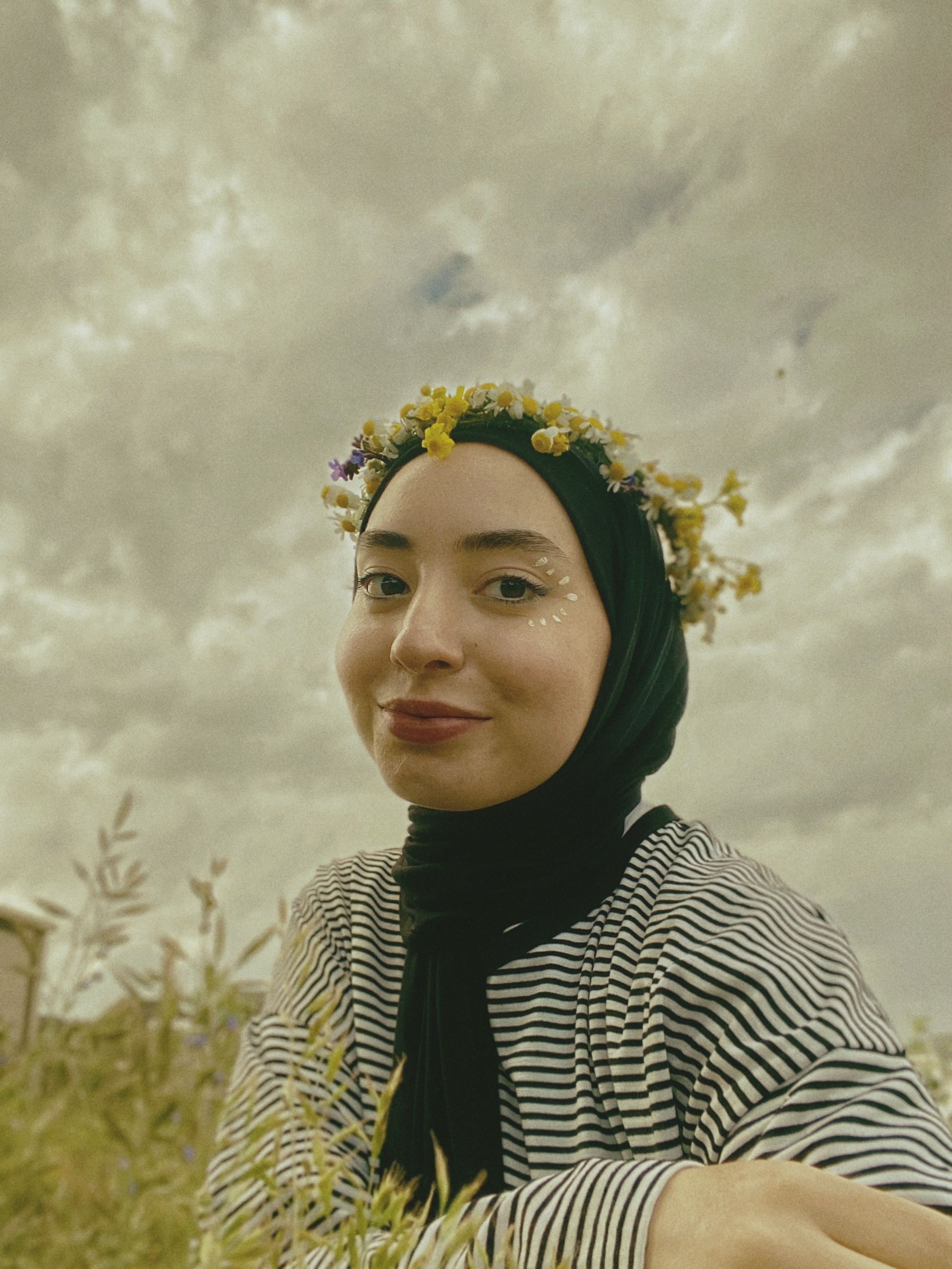 Portrait of a woman wearing a flower garland outdoors, depicting a cheerful spring mood.