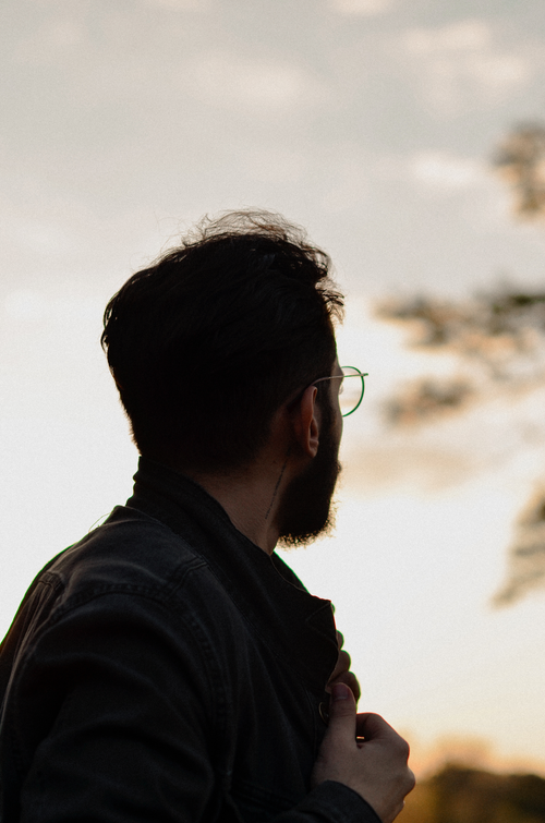 Free A man with eyeglasses gazes into the sunset, exuding calm and quiet reflection. Stock Photo