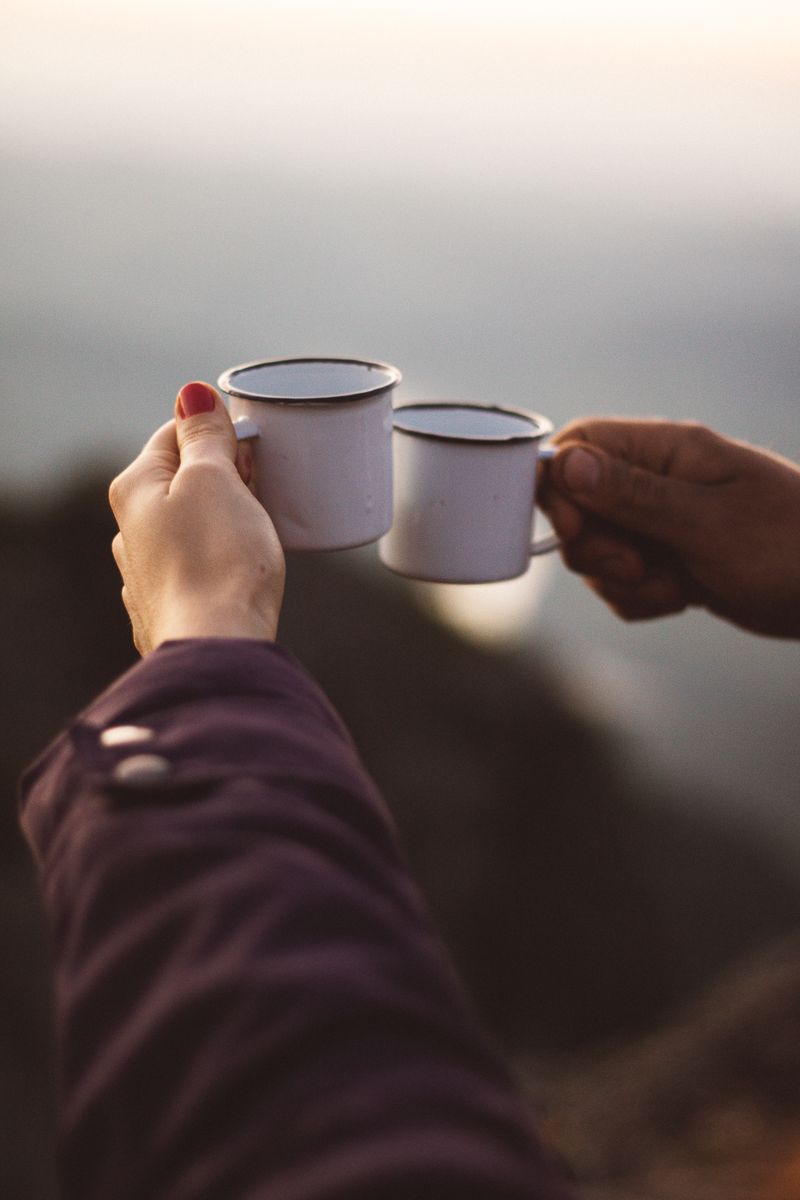 Two metal cups raised in a toast at golden hour