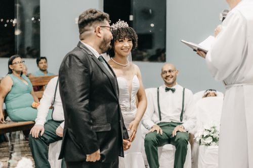 Free Bride and groom smiling during a wedding ceremony inside a church with guests in attendance. Stock Photo