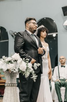 A stylish indoor wedding ceremony featuring a bride in a gown and groom in a suit, captured in natural light.