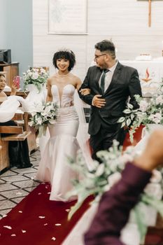 A joyful bride and groom walking down the aisle in a beautifully decorated church setting. - Fotografer Sidoarjo