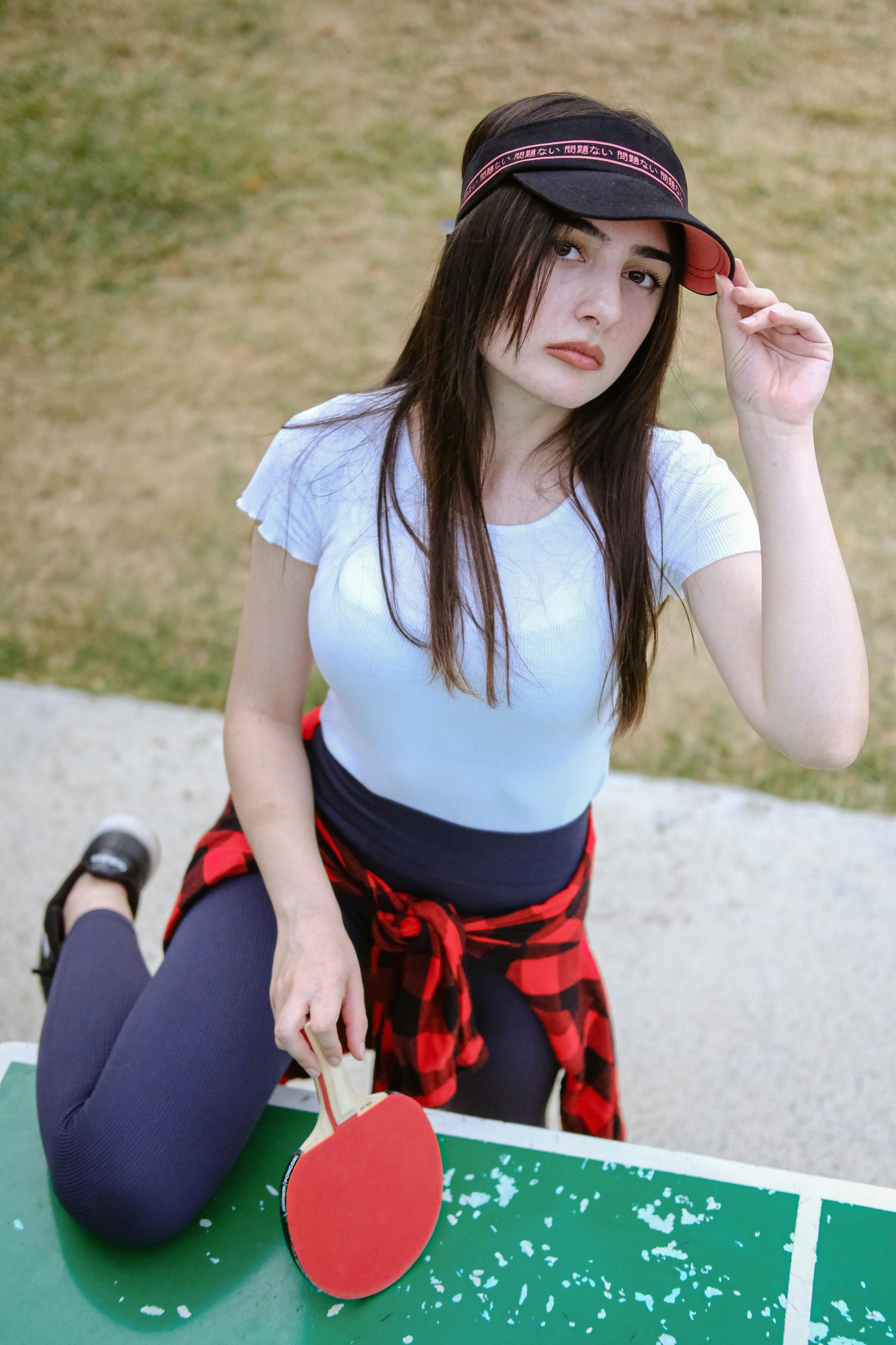 a girl in a hat and plaid shirt sitting on a table