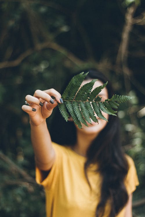 Selective Focus Photography Of Woman Holding Leaf