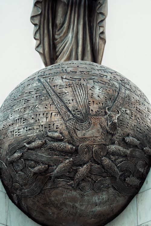 Free Bronze sphere sculpture featuring fish and abstract patterns, captured in close-up view. Stock Photo