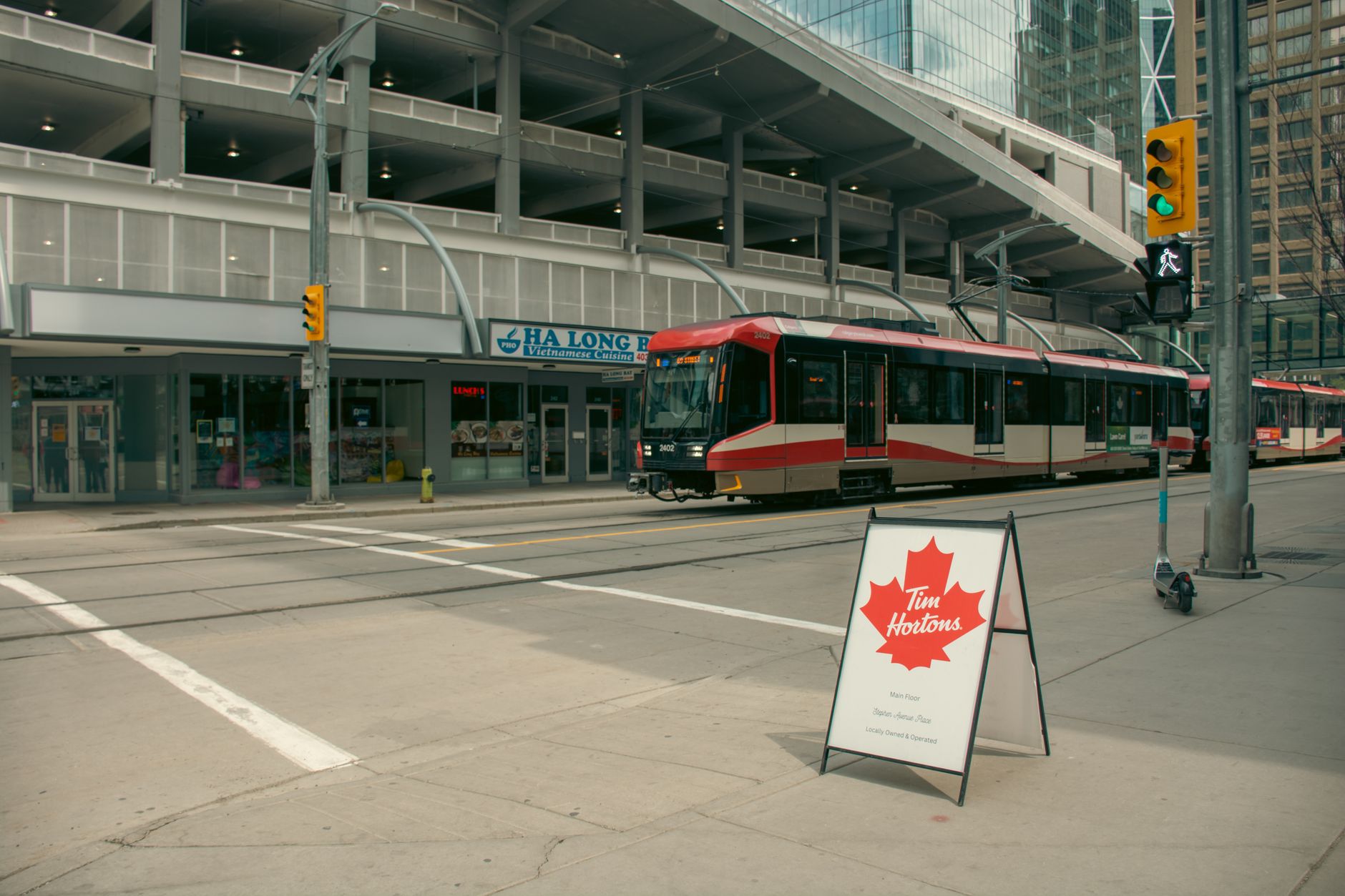 Tram crossing a city street with a Tim Hortons sign, capturing urban Canadian life.