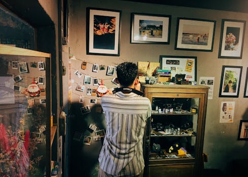 一名男子在家中探索他的个人画廊，里面陈列着镶框的照片和老式相机