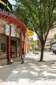 Scenic view of a Chinatown street in Calgary featuring distinctive red architecture and lush trees.