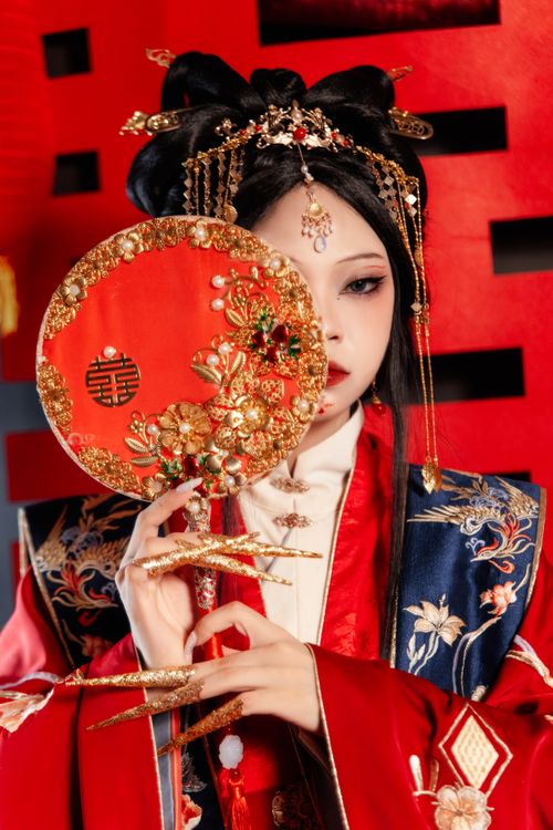 Free Portrait of an Asian woman in intricate traditional attire holding a decorative fan. Stock Photo