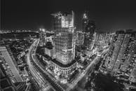 这张黑白图像令人惊叹，展现了夜间充满活力的城市景观，包括建筑和繁忙的交通