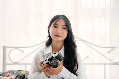 Portrait of a Woman with Camera Sitting on a Bed