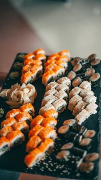 Colorful assortment of sushi rolls on a black serving plate, showcasing traditional Japanese cuisine.