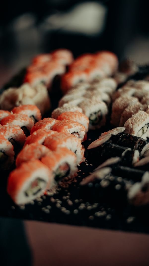 A close-up shot of a sushi roll, with the rice and filling visible, and the nori seaweed wrapping it neatly