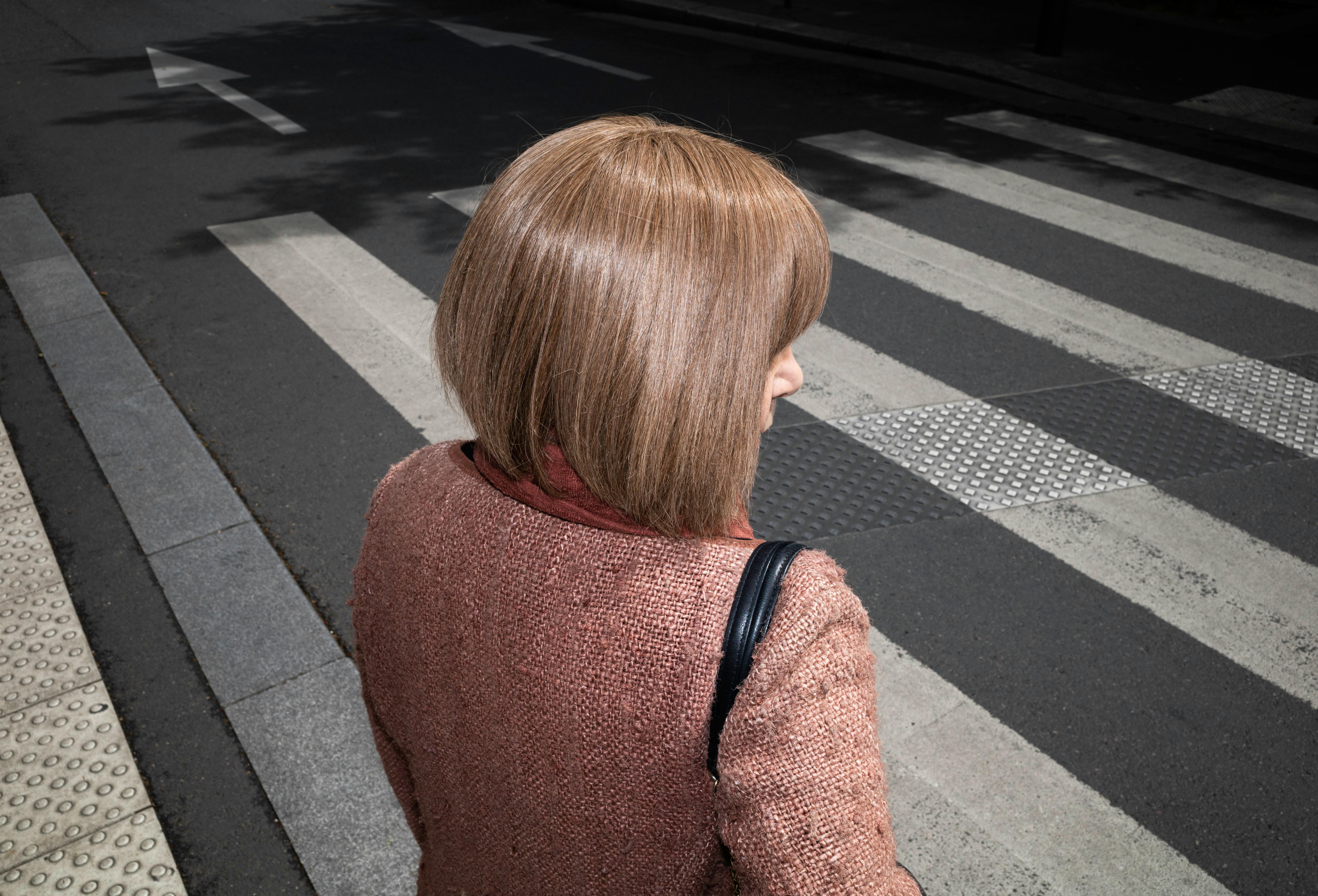 Stylish adult woman with blonde hair crossing an urban street's pedestrian lane.
