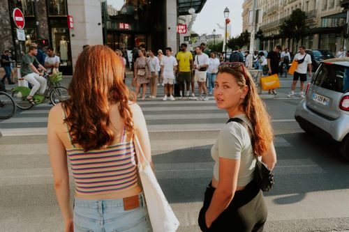 Free Two young women navigate a busy urban crosswalk, surrounded by city life and pedestrians. Stock Photo