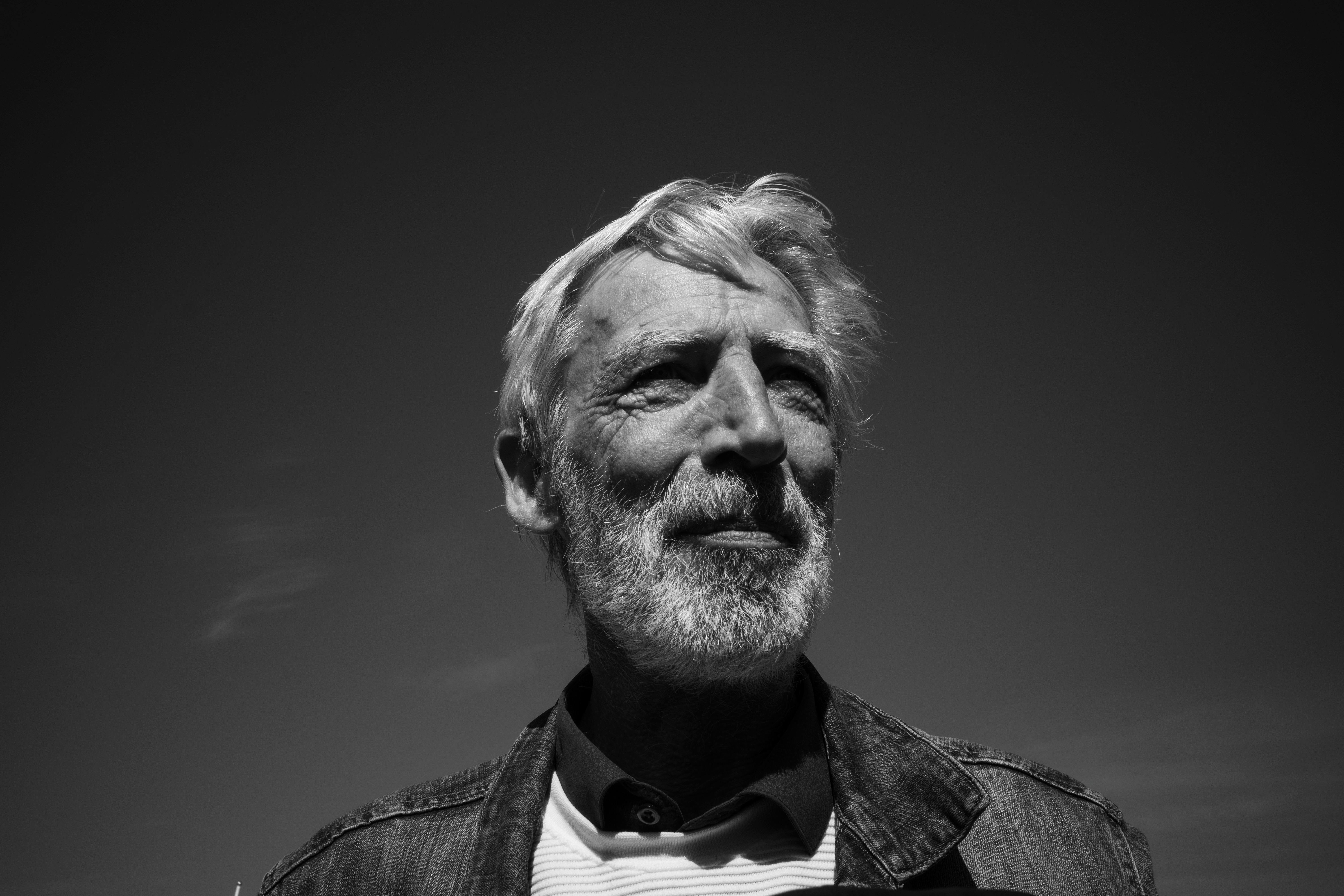 Thoughtful black and white portrait of a senior man with beard outdoors.