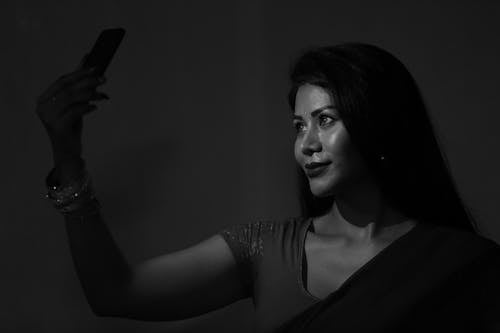Young Woman Holding a Smartphone in her Hand and Taking a Selfie 