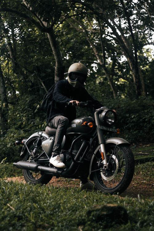 Free A motorcyclist wearing a helmet rides through a lush green forest path. Stock Photo