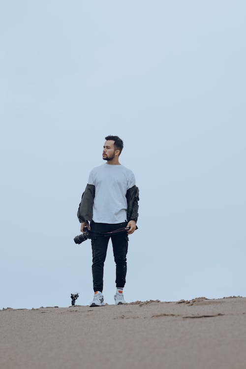 Man Standing with Camera on Sand