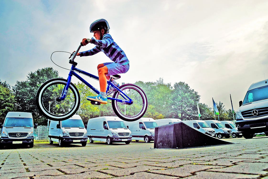 Kostenlos Junge Im Schwarzen Nussschalenhelm Auf Blauem Bmx Fahrrad, Das Nach Dem Abheben Auf Der Rampe Hangtime Hat Stock-Foto