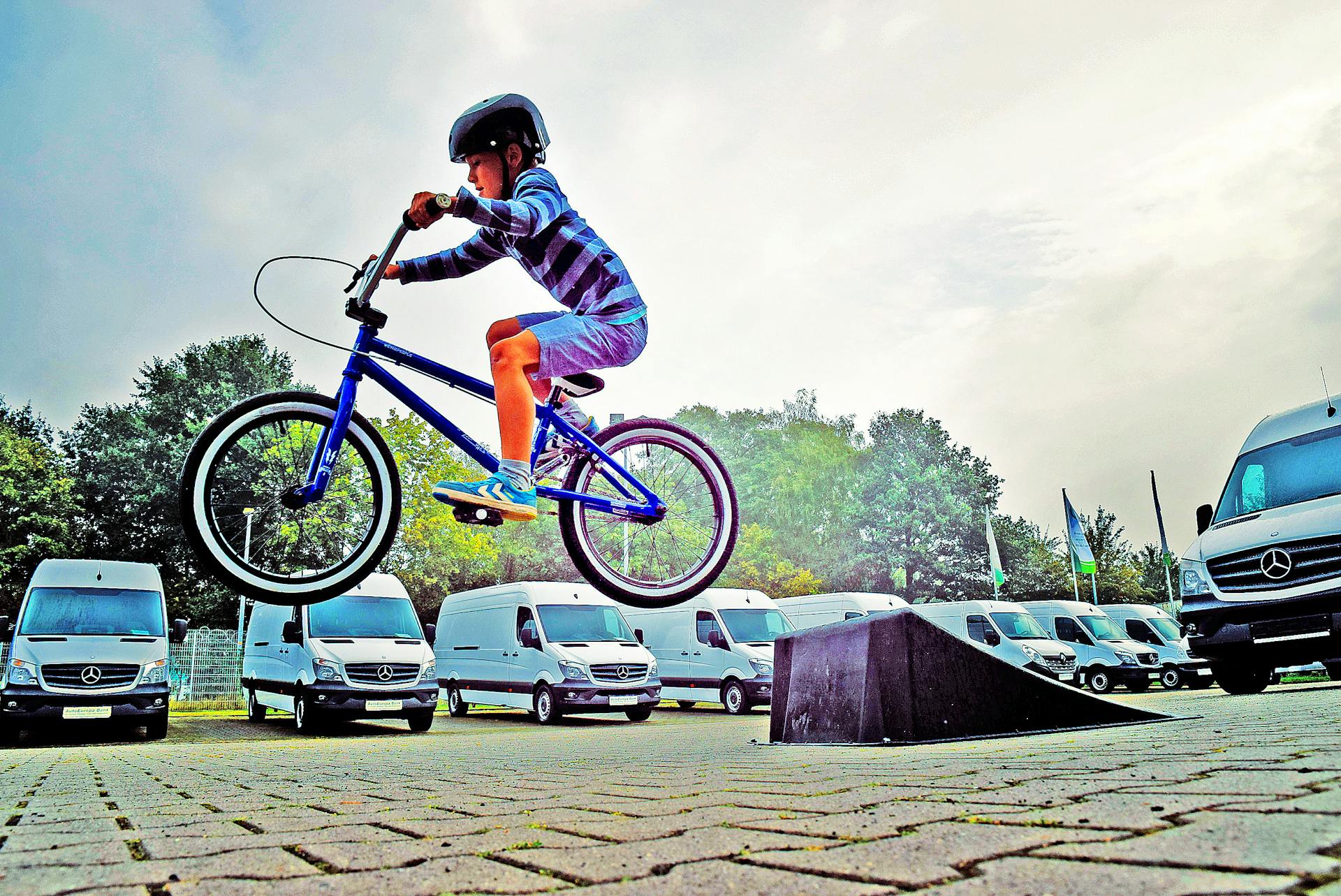 Boy in Black Nutshell Helmet on Blue Bmx Bike Having Hangtime After Taking Off on Ramp