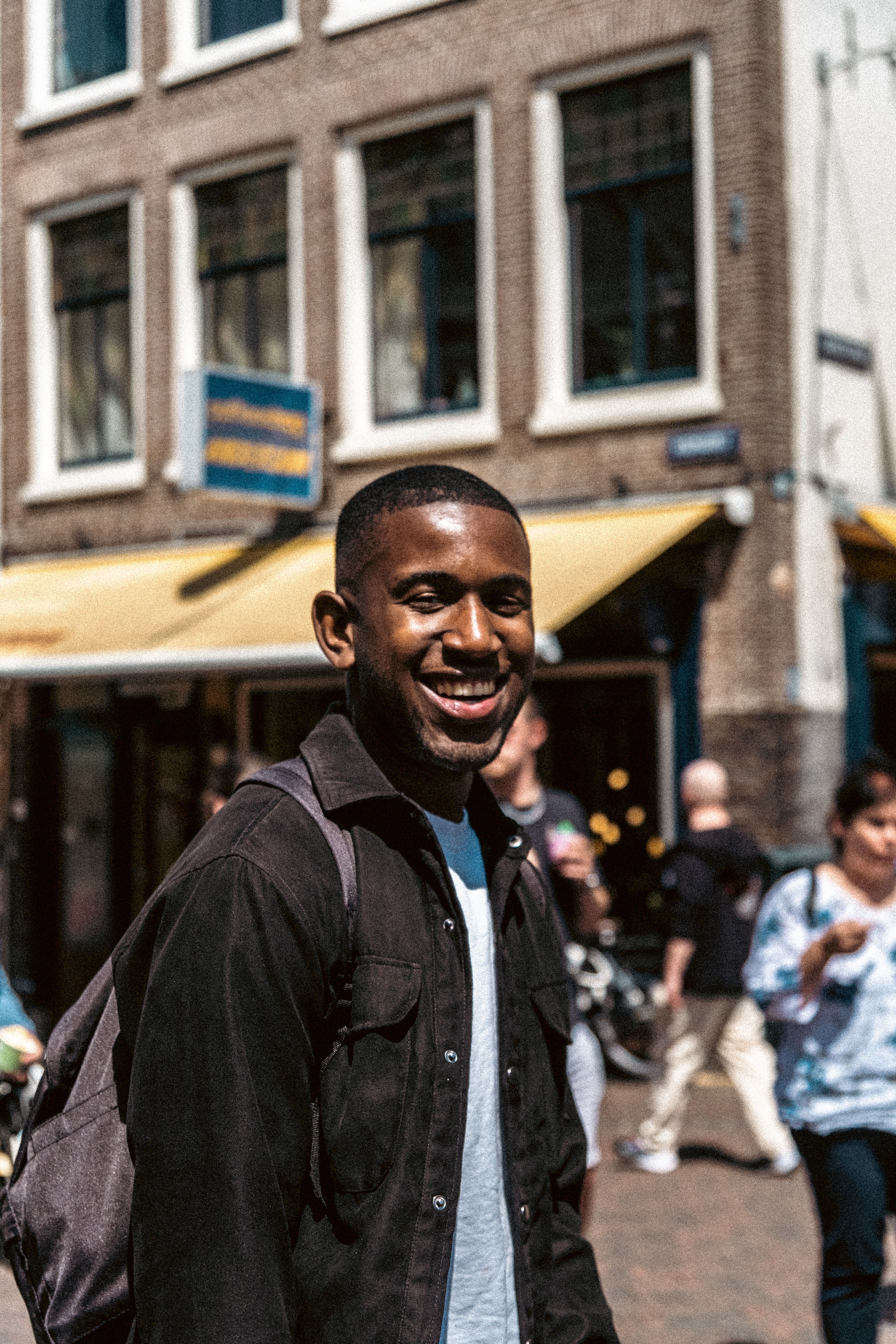 Portrait of a smiling man in urban setting, capturing modern fashion and joyful expression.