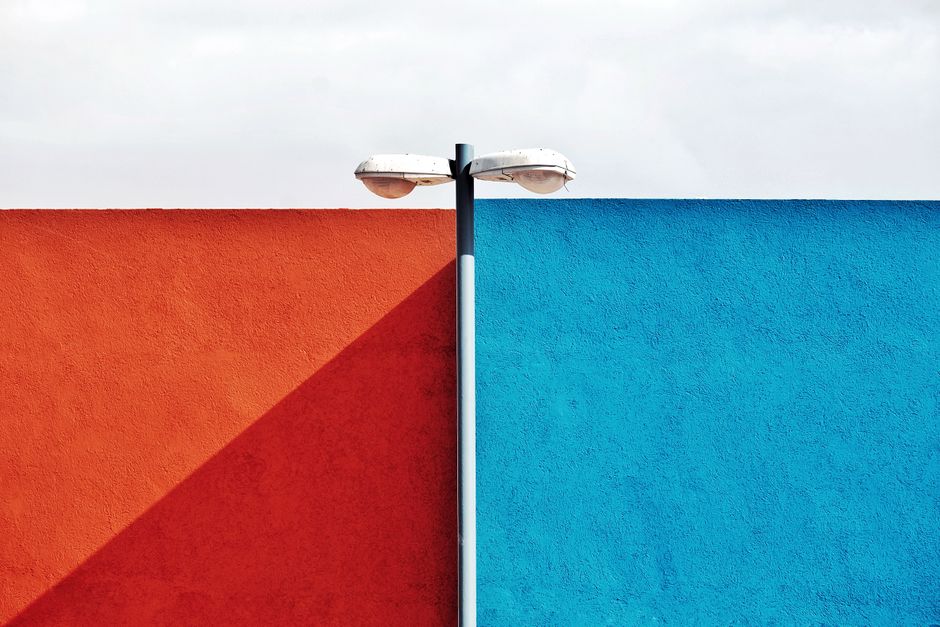 A modern street lamp divides red and blue walls, creating a striking urban contrast.