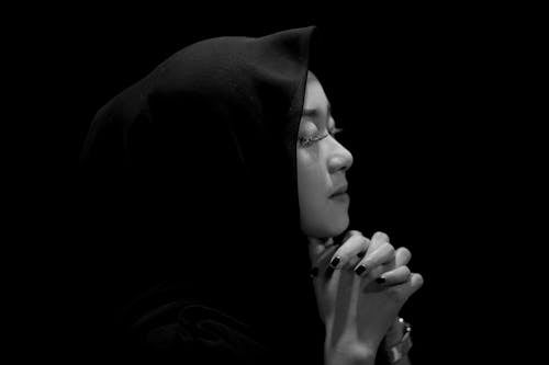 Foto profissional grátis de fundo preto, hijab, mãos entrelaçadas