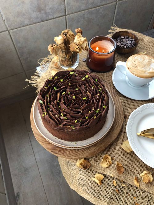 Free A rich chocolate cake paired with a cappuccino, set in a cozy atmosphere with a lit candle. Stock Photo
