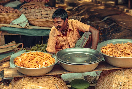 A street vendor selling vegetables and snacks at an outdoor market stall.