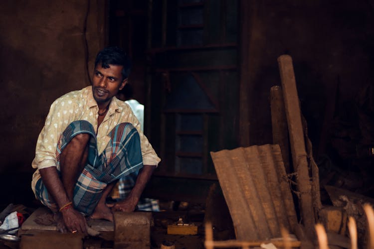 Man Squatting In Workshop