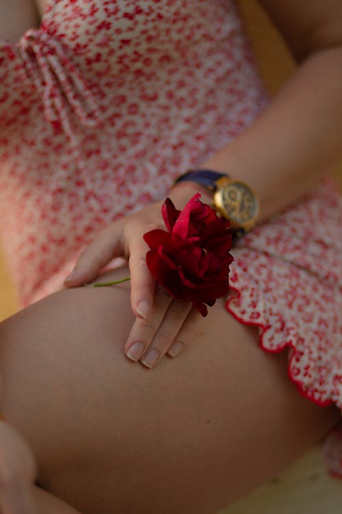 Woman Hand Holding Flower over Leg