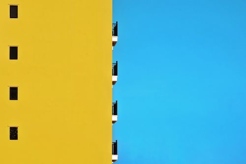 Free Bright yellow building facade contrasts with clear blue sky in Hội An, Vietnam. Stock Photo