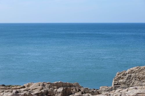Free Rocky seashore with a vast blue ocean and horizon in Weihai, Shandong, China. Stock Photo