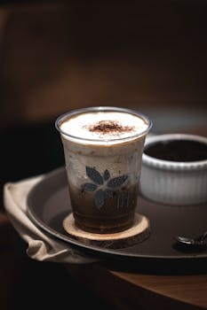 A close-up photo of a fresh iced coffee served on a tray with a wooden coaster, perfect for refreshing and energetic moments.