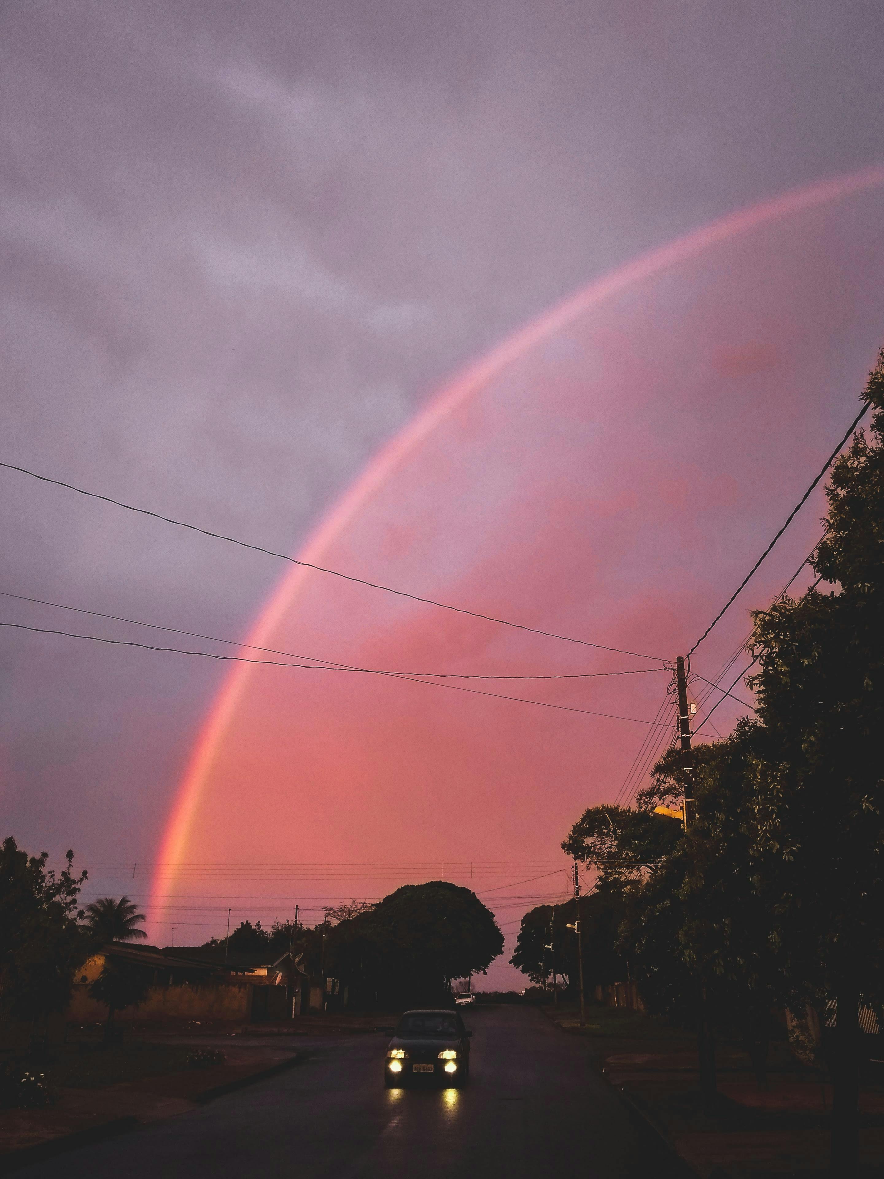 一条令人惊叹的彩虹划过安静的街道，映衬在色彩缤纷的日落之中